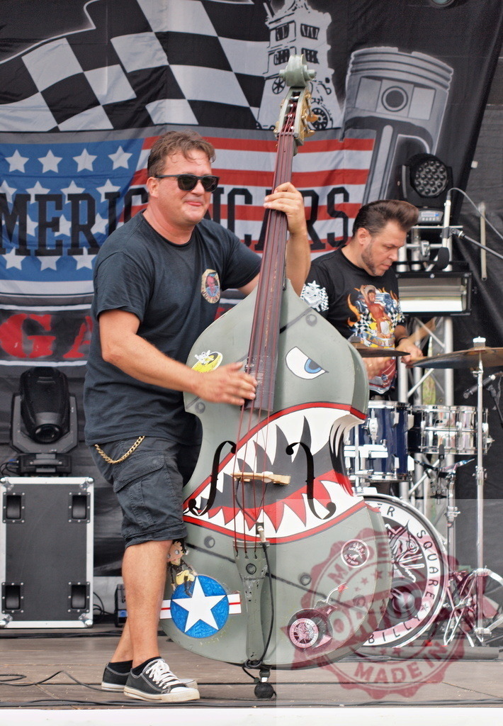 Rockabilly band performing live concert with custom double bass | Musician playing an upright bass with shark mouth nose art design on stage - Realized with Pictrs.com