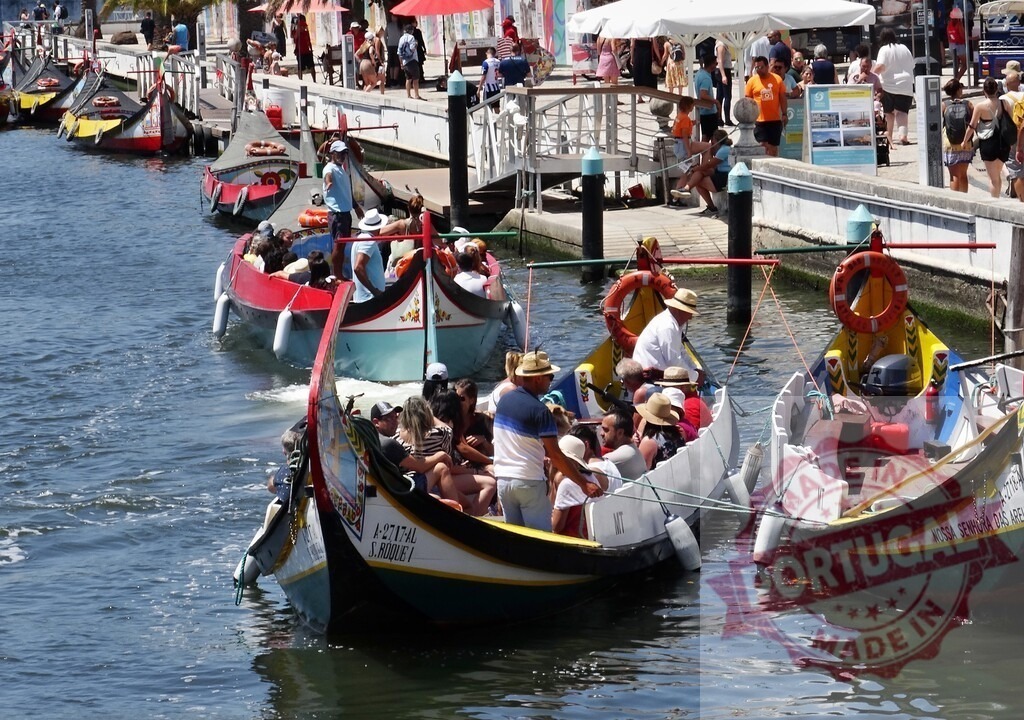 Moliceiro boats cruising on Aveiro canal with tourists | Moliceiro boats are navigating the canals of Aveiro packed with tourists enjoying the sunny day - Realized with Pictrs.com