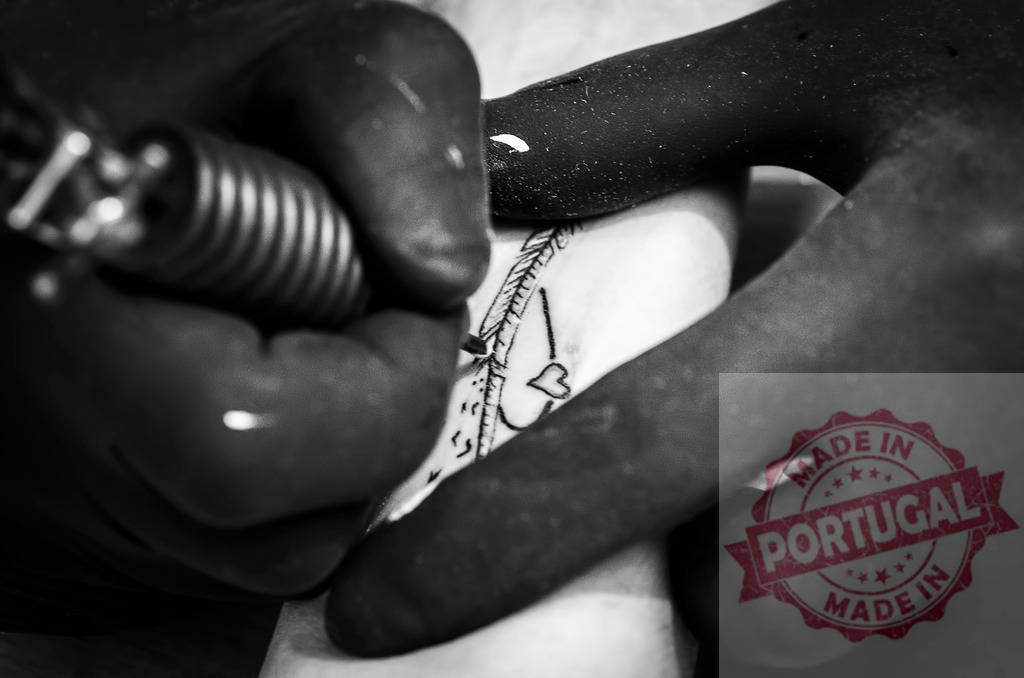 Tattoo artist creating heart and feather skin art | Tattoo artist wearing black gloves applying new design on skin - Realized with Pictrs.com