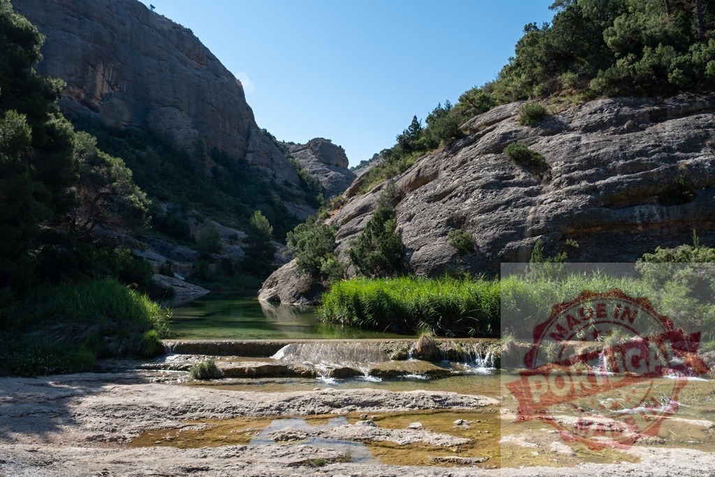 Canyon river flowing over waterfalls creating tranquil landscape | River flowing through a canyon with waterfalls, surrounded by rock formations and green vegetation - Realisiert mit Pictrs.com