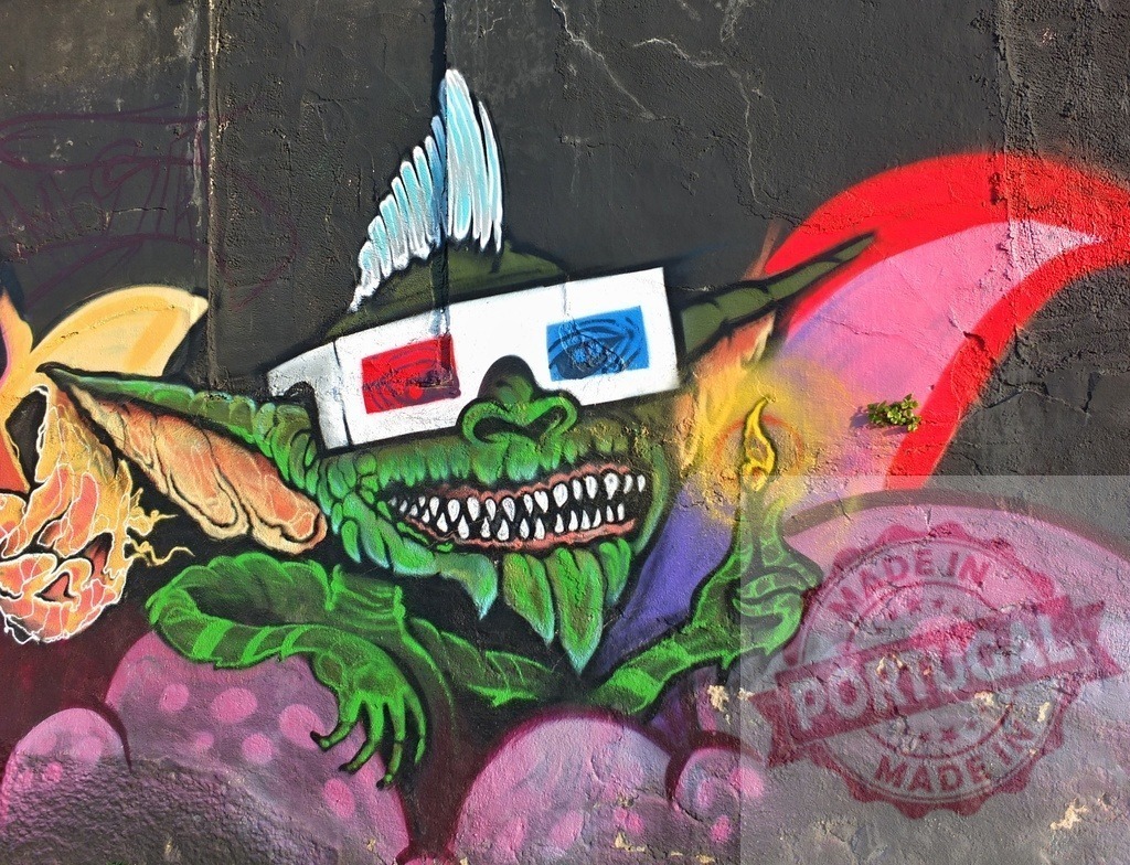 Green gremlin creature wearing 3D glasses street art | Green monster wearing 3D glasses painted as urban graffiti on a textured wall - Realized with Pictrs.com