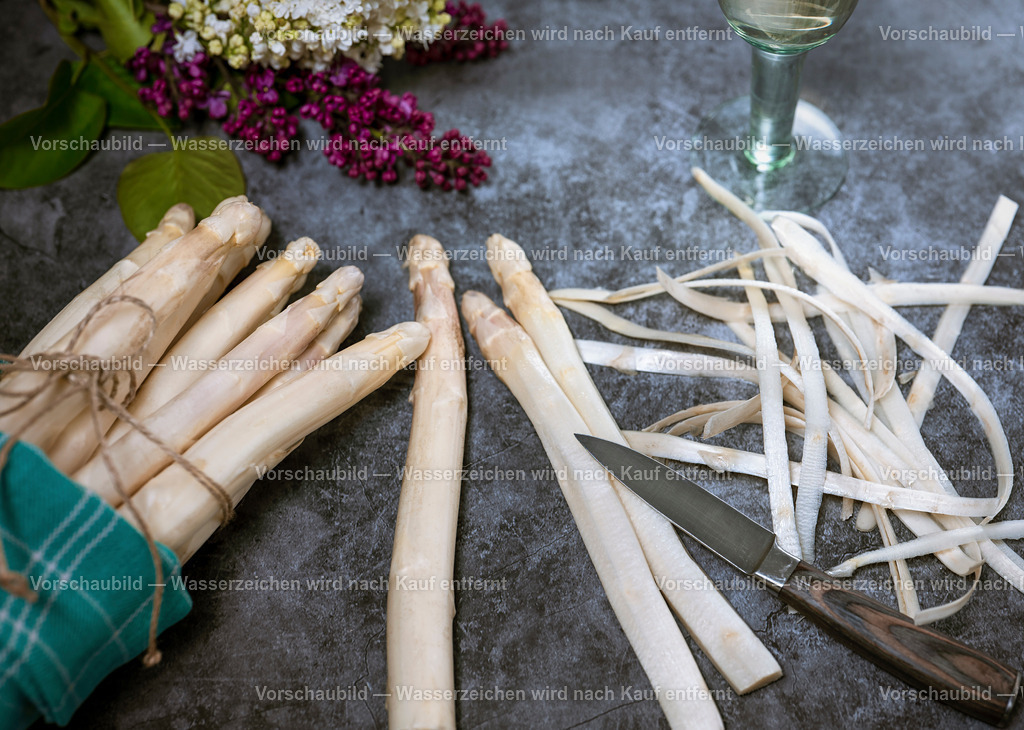 Frischer weißer Spagel beim Schälen | Frischer weißer Spagel beim Schälen. Dekoriert mit einen Glas Weissweinn, Spargelschalen, Messer und Fliederstrauß. - Realisiert mit Pictrs.com