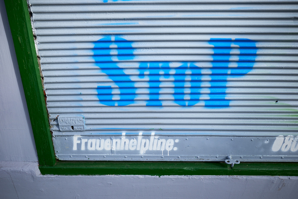 geschlossene Jalousie mit Aufschrift STOP und Frauenhelpline | Wien, Austria - March 15, 2023: Details am Wiener Gürtel; geschlossene Jalousie mit Aufschrift STOP und Frauenhelpline. - Realisiert mit Pictrs.com
