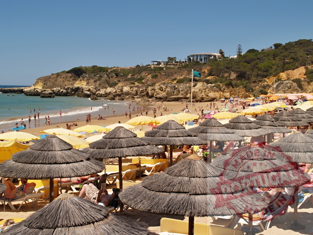 Algarve beach with thatched umbrellas and people | Crowded beach in Portugal with many people enjoying summer vacation under straw umbrellas - Realisiert mit Pictrs.com