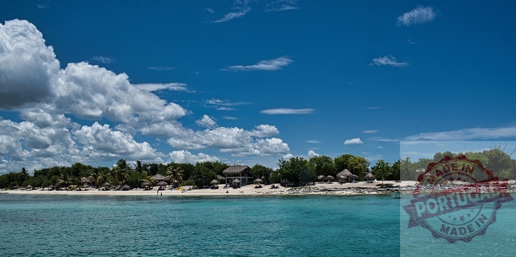 Caribbean island beach resort with turquoise water and palm trees | Tropical island landscape featuring a white sand beach, lush green trees, and blue sky - Realized with Pictrs.com