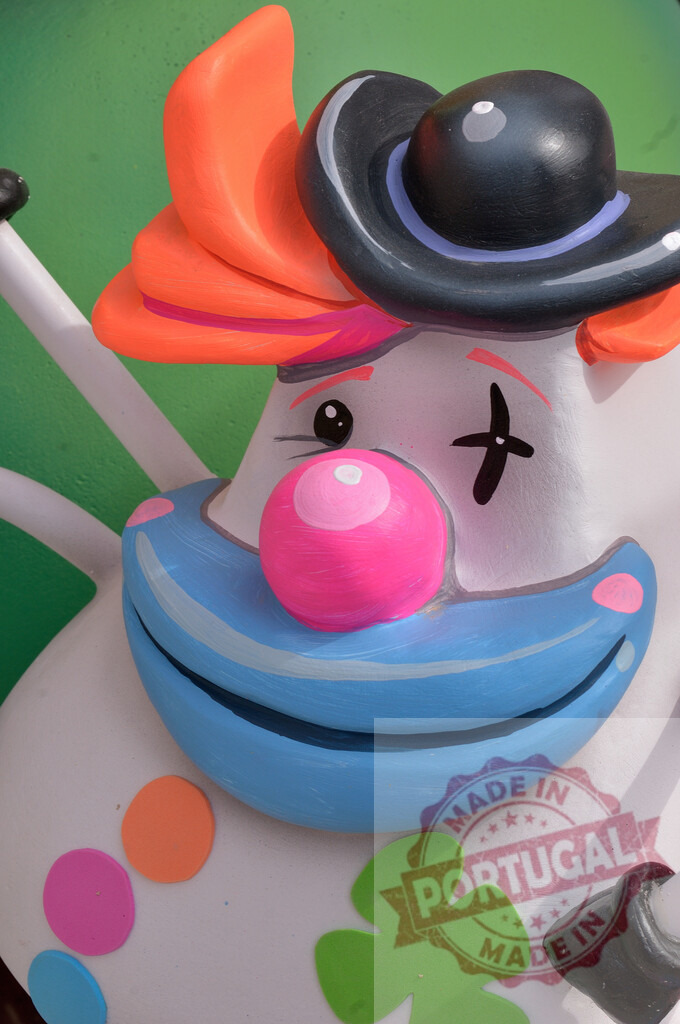 Colorful clown sculpture with pink nose and black hat. Fallas Fiestas Communidad Valenciana | Close up of a smiling clown character sculpture with bright orange hair and makeup - Realized with Pictrs.com