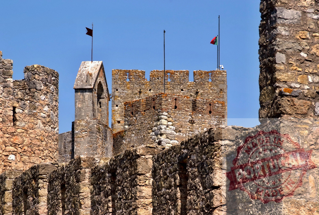 Templar castle battlements with Portuguese flag flying under blue sky | Stone walls and battlements of a medieval fortress in Tomar, Portugal under clear blue sky - Realisiert mit Pictrs.com