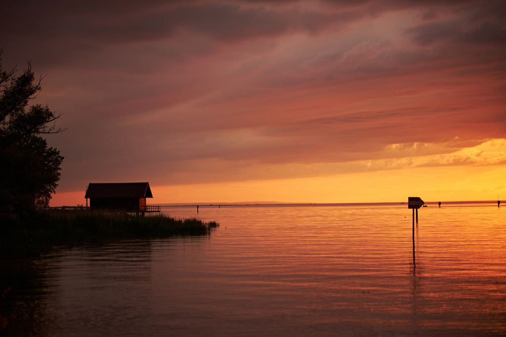 Romantischer Sonnenuntergang am Bodensee | Bregenz, Austria - June 07, 2024: Romantischer Sonnenuntergang am Bodensee mit Blick auf eine Badehütte. - Realisiert mit Pictrs.com