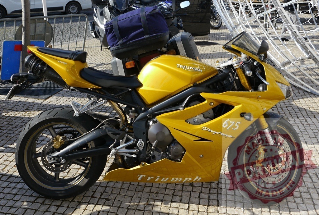 Yellow Triumph Daytona 675 sportbike parked on cobblestone street | Yellow Triumph Daytona 675 sportbike parked outdoors on a sunny day - Realisiert mit Pictrs.com