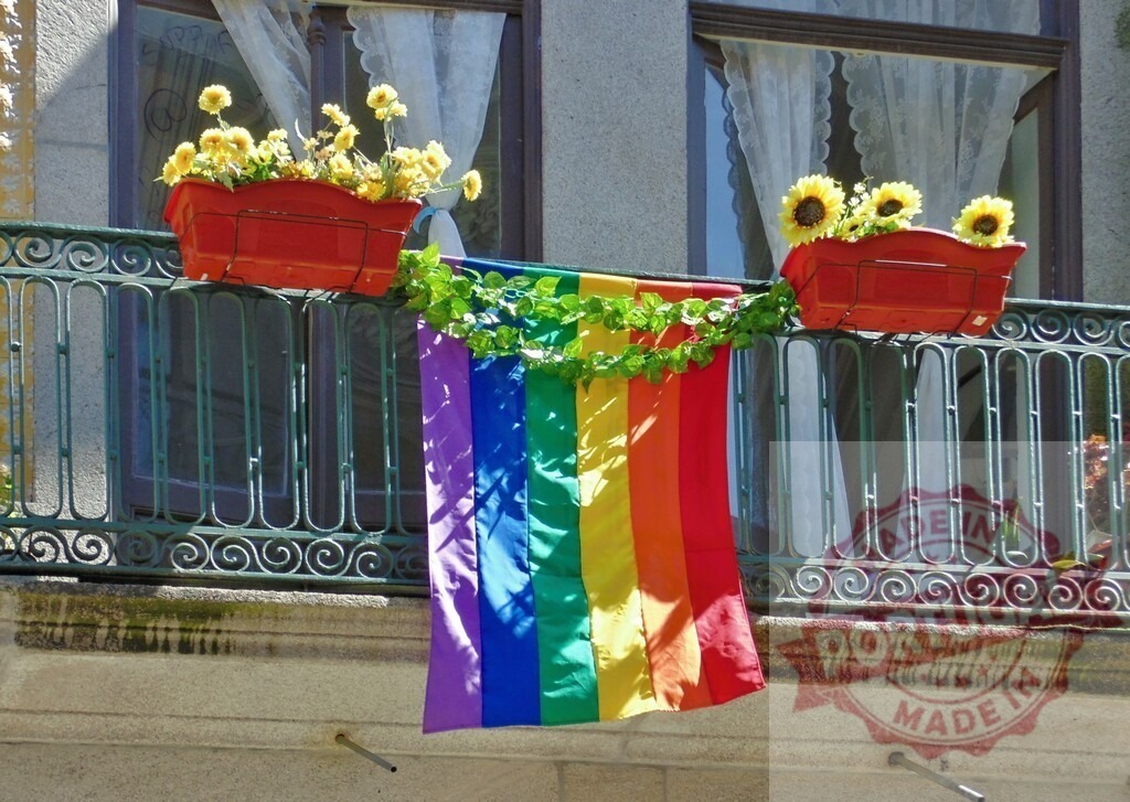 Rainbow flag on balcony reflecting LGBTQ+ pride and support | Rainbow flag hanging on a building balcony showing support for the LGBTQ+ community - Realized with Pictrs.com