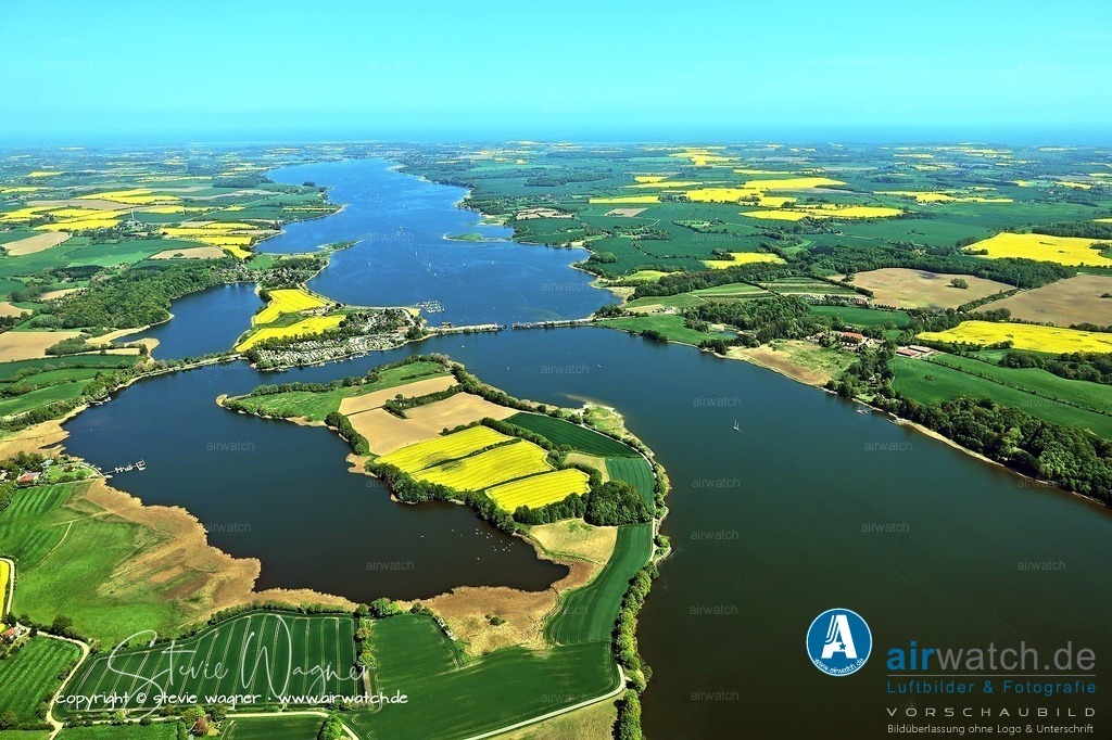 Luftbild Ostseefjord Schlei, Boren-Lindaunis Schleibrücke, Campingplatz Lindaunis, Sportboothafen Lindaunis | Die Schlei, ein schmaler Meeresarm der Ostsee in Schleswig-Holstein, trennt die Landschaften Angeln und Schwansen und ist seit dem Mittelalter ein bedeutender Handelsweg im Ostseeraum. Ihre historische Bedeutung reicht bis in die Wikingerzeit zurück, als die Siedlung Haithabu, die 1066 zerstört wurde, als wichtiger Meereshafen diente, von dem aus Schiffe bis nach Schweden und Griechenland segelten.