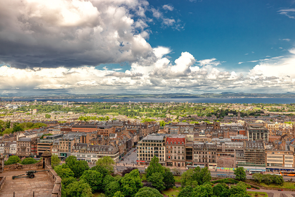 Weltberühmter Panoramablick über Edinburgh------Schottland | Das ausgewählte Bild zeigt den weltberühmten Panoramaausblick von den Mauern des Edinburgh Castle über die schottische Hauptstadt.Die Aufnahme wurde direkt auf dem Gelände von Edinburgh Castle (gelegen auf dem Castle Rock) gemacht. Am linken unteren Bildrand ist eine historische Kanone der Festungsanlage zu erkennen.Blickrichtung: Der Blick geht nach Norden/Nordosten über die tiefer liegenden Princes Street Gardens hinweg direkt auf die Gebäude der Princes Street und das dahinter liegende Viertel New Town.Hintergrund: In der Ferne sieht man den Meeresarm Firth of Forth, der das Stadtgebiet vom gegenüberliegenden Ufer der Region Fife trennt - Realisiert mit Pictrs.com