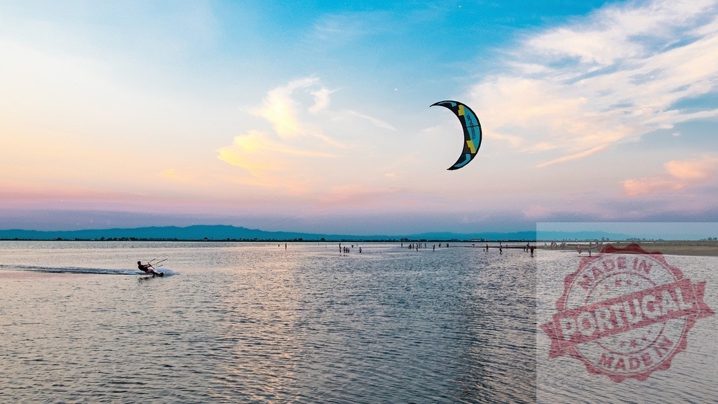 Person kitesurfing on water at sunset | Person enjoying kitesurfing water sport with a colorful kite moving on the water during sunset - Realized with Pictrs.com