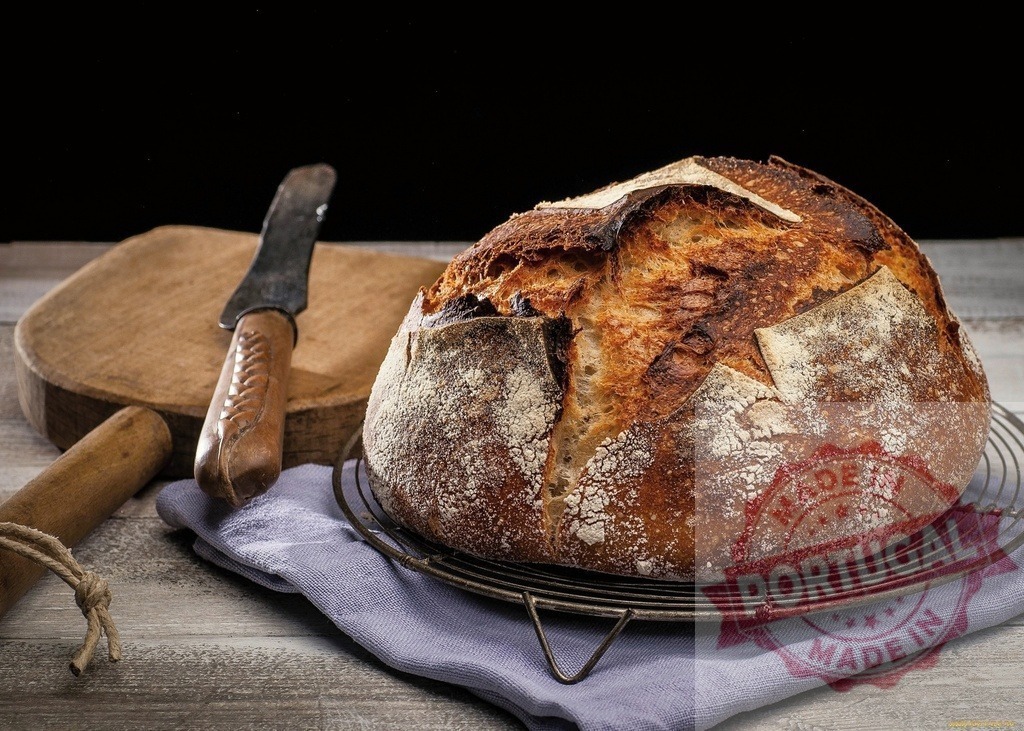 Freshly baked sourdough bread loaf on cooling rack | Rustic homemade artisan sourdough bread on a cooling rack with knife and cutting board - Realisiert mit Pictrs.com