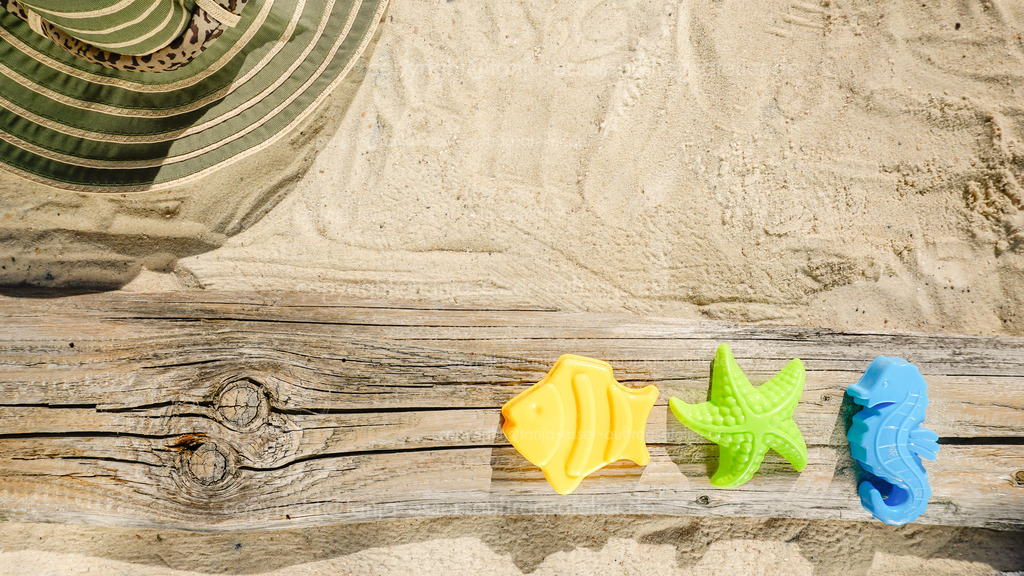 summer beach_ sun hat and colorful toys D | Sommerlicher Familientag am Meer. Hintergrund zeigt Sonnenhut, Strand Spielzeug und Sand mit Copy Space.