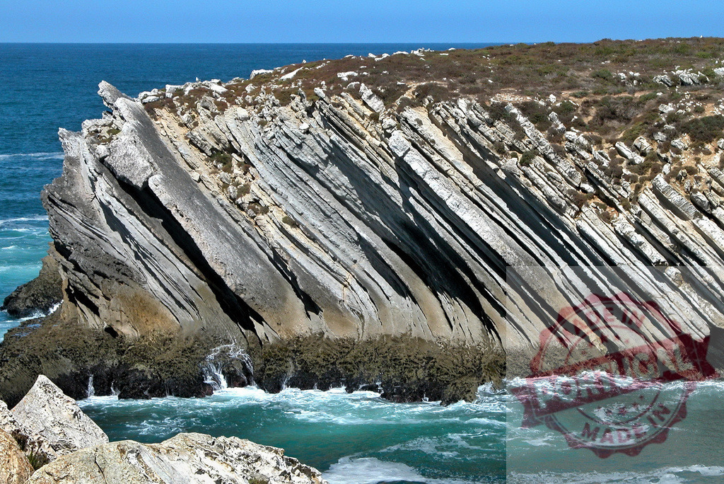 Cabo Sardão coastal cliff showcasing tilted sedimentary rock strata. Centro Portugal | Tilted rock layers forming a dramatic coastal cliff eroded by ocean waves and geology - Realized with Pictrs.com