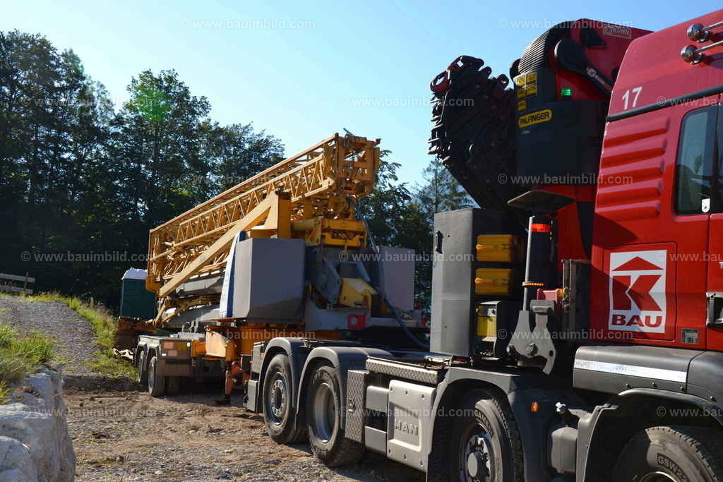 Anlieferung Baukran | Rote Sattelzugmaschine mit angehängtem Kran auf Kranachsen