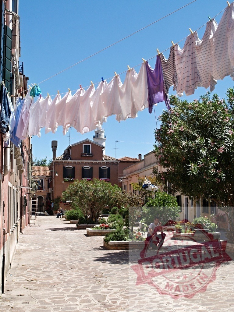 Laundry hanging on clothesline in typical Venetian square | Clothes are drying on a clothesline in a Venetian square, with a man sitting in the shade - Realized with Pictrs.com