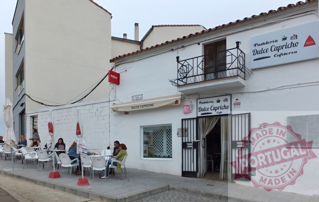 Pasteleria Dulce Capricho cafe with people relaxing outdoors | People enjoying drinks and conversation at a sidewalk patio cafe in a white building - Realized with Pictrs.com