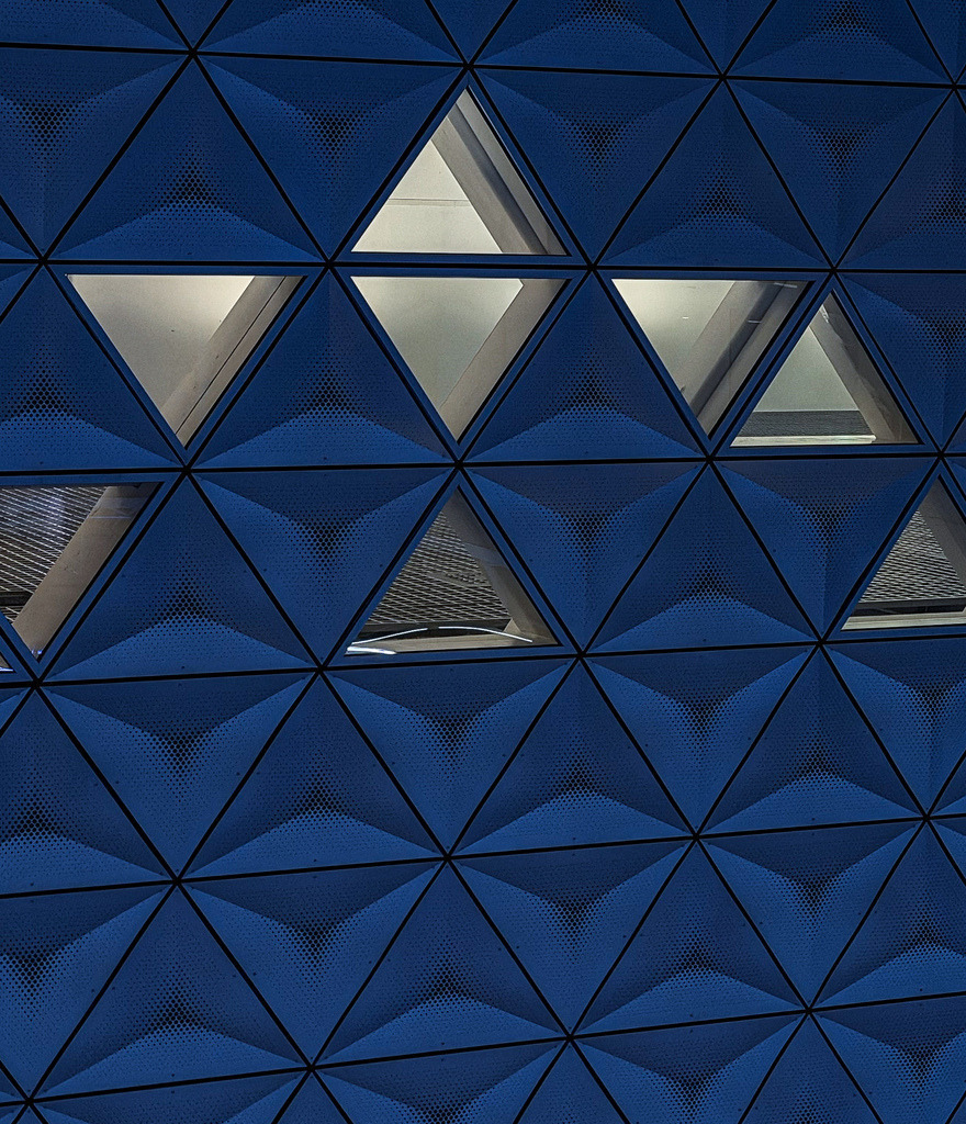 Blaue Geometrie – Abstrakte Dreiecks-Fassade | Futuristische Architektur und grafische Perfektion. Diese abstrakte Fotokunst fängt die dreidimensionalen, blauen Dreiecks-Elemente einer modernen Gebäudefassade ein. Das faszinierende Spiel aus Licht, Schatten und kühlem Blau verleiht modernen Wohnräumen, minimalistischen Lofts oder stylischen Büros eine urbane Tiefe. Ein exklusiver Eyecatcher als großformatiger Fine Art Print, edles Alu-Dibond oder unter Acrylglas. - Realisiert mit Pictrs.com