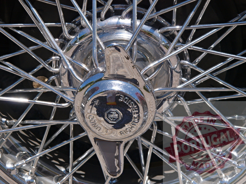 Close-up of shining chrome wire wheel with knock-off hubcap reflecting sunlight | Polished chrome wire wheel hub with MG logo and spinner knock-off reflects sunlight - Realisiert mit Pictrs.com