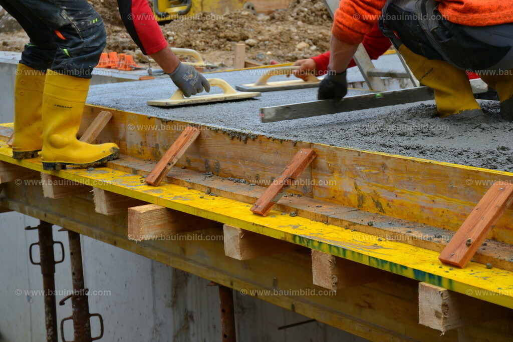 Beton glätten | Arbeiter beim Abziehen und Glätten von Beton einer Kragplatte