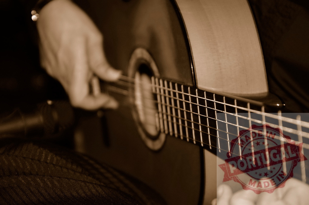 Musician playing acoustic guitar during live performance | Musician's hands strumming classical guitar strings, creating music during a concert in sepia tones - Realized with Pictrs.com
