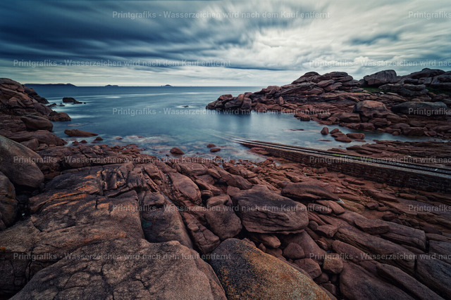 Felsenbucht an der bretonischen Küste | Raue Küstenlandschaft in der Bretagne mit rötlichen Granitfelsen, ruhigem Meer und dramatischem Wolkenhimmel. Die weiche Wasserbewegung und die natürlichen Felsstrukturen verleihen der Szene eine stille, kraftvolle und maritime Atmosphäre. - Realisiert mit Pictrs.com