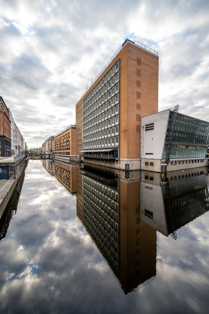 Moderne Architektur im Spiegel des Wassers | Moderne Hamburger Architektur trifft auf eine nahezu ruhige Wasseroberfläche. Die klare Spiegelung verstärkt die geometrische Wirkung des Gebäudes und verbindet Himmel, Fassade und Wasser zu einer harmonischen Komposition. - Realisiert mit Pictrs.com