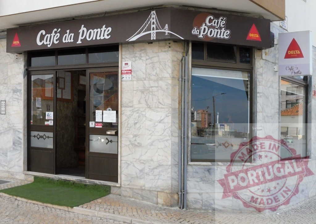 Café da Ponte storefront with Delta Cafés branding in Portugal | Café da Ponte, a coffee shop with marble facade, featuring Delta Cafés logo - Realisiert mit Pictrs.com