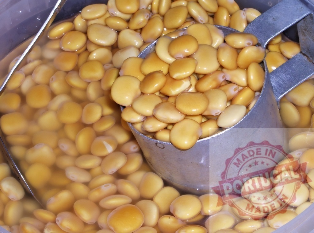 Lupini beans soaking in brine with metal scoop | Yellow brined lupin beans soaking in water with a metal scoop - Realized with Pictrs.com