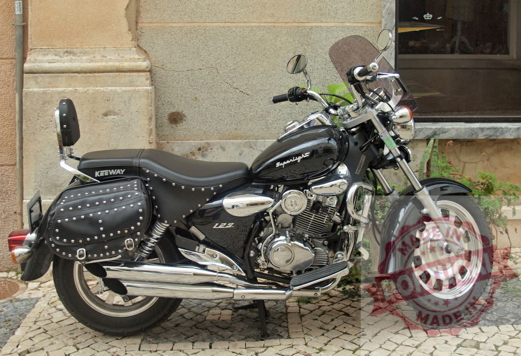 Keeway Superlight 125 cruiser motorcycle parked on street | Keeway Superlight 125 cruiser motorcycle standing on a cobblestone street - Realized with Pictrs.com
