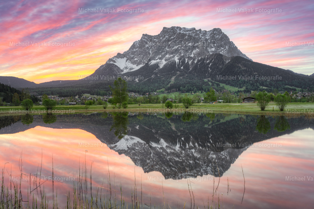 Die Tiroler Seite der Zugspitze | Blick auf die Zugspitze von Tirol aus gesehen. Während eines herrlichen Sonnenaufgangs spiegelt sich das Bergmassiv im noch ruhigen Wasser eines Teiches. - Realisiert mit Pictrs.com