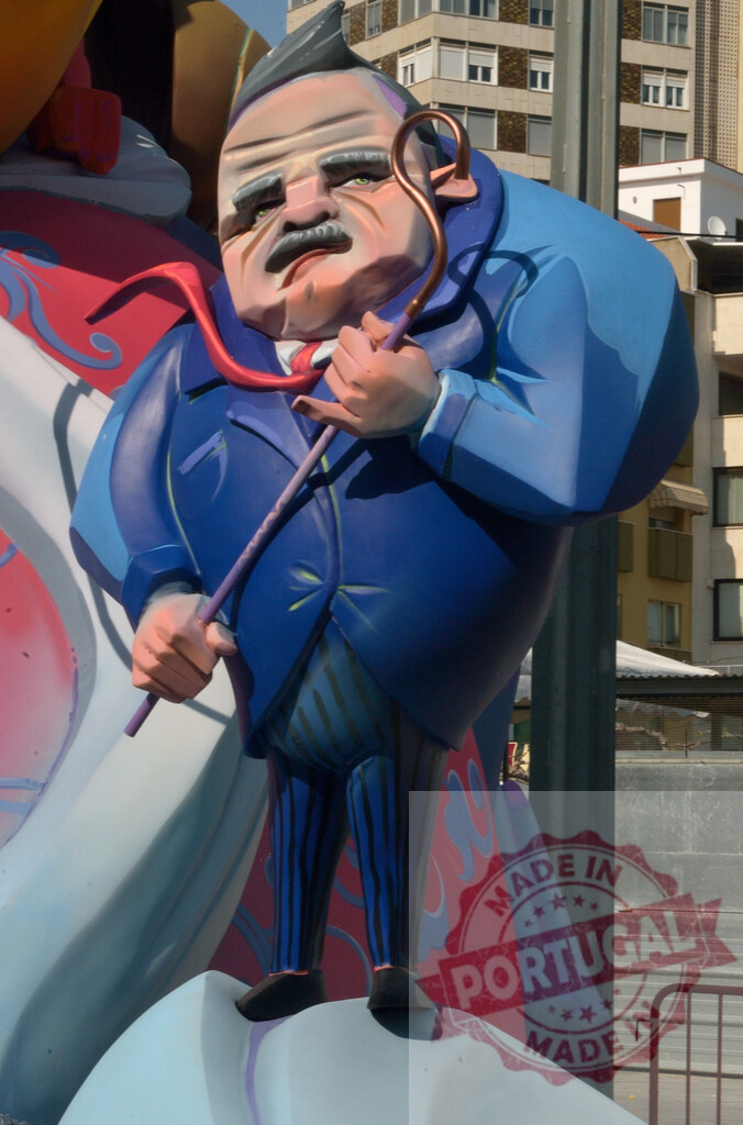 Fallas festival caricature statue of a man. Fallas Fiestas Communidad Valenciana | Fallas festival ninot depicting a satirical man in a blue suit holding a cane - Realized with Pictrs.com