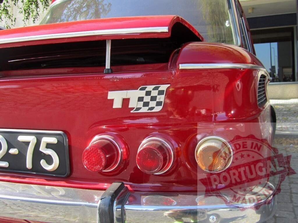 Rear view of red Renault 8 Gordini showing open trunk and racing flag | Close-up of the back of a vintage red Renault 8 Gordini with its trunk open, showcasing the checkered racing flag logo - Realisiert mit Pictrs.com