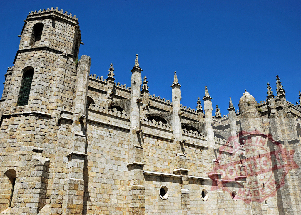 Cathedral of Guarda facade showing Gothic architecture and medieval heritage. Region Norte - Portugal | Guarda Cathedral, Portugal, displaying its stone facade, spires, and historic details under a blue sky - Realized with Pictrs.com
