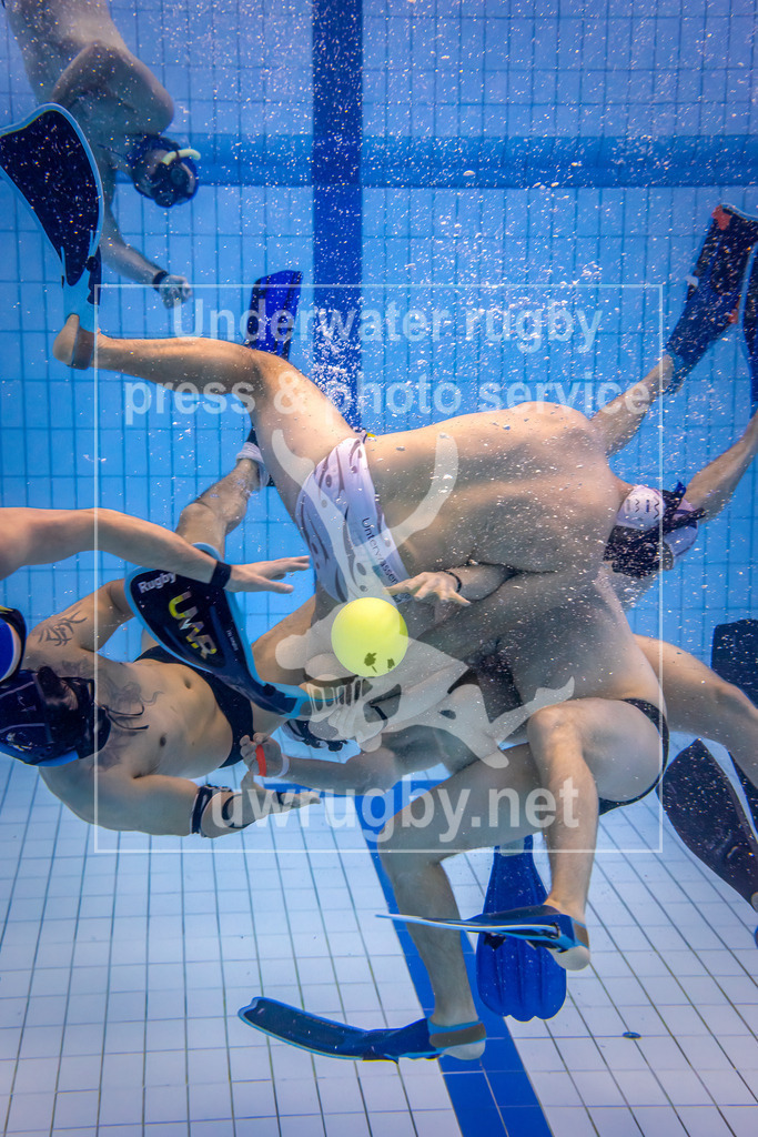Unterwasser-Rugby 5. Spieltag 1. Bundesliga Süd (Saison 2023/24) | Spiel TSV Malsch in weiß gegen Tauchclub Bamberg in blau. Zweikampf in der Mitte des Spielfeld, der körperbetonte Angriff des Malscher Spielers kann den Bamberger Spieler nicht an den sauberen auf seinen Mitspieler Felix Walcher hintern. - Realisiert mit Pictrs.com
