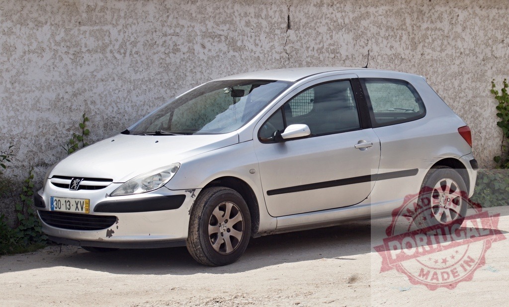 Silver Peugeot 307 compact three-door hatchback car | Silver Peugeot 307 hatchback parked on a dirt road by a textured wall - Realized with Pictrs.com