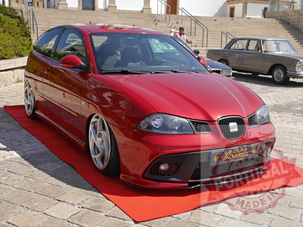 Red SEAT Ibiza lowrider car at show | Red SEAT Ibiza customized car on a red carpet at an outdoor car show - Realisiert mit Pictrs.com