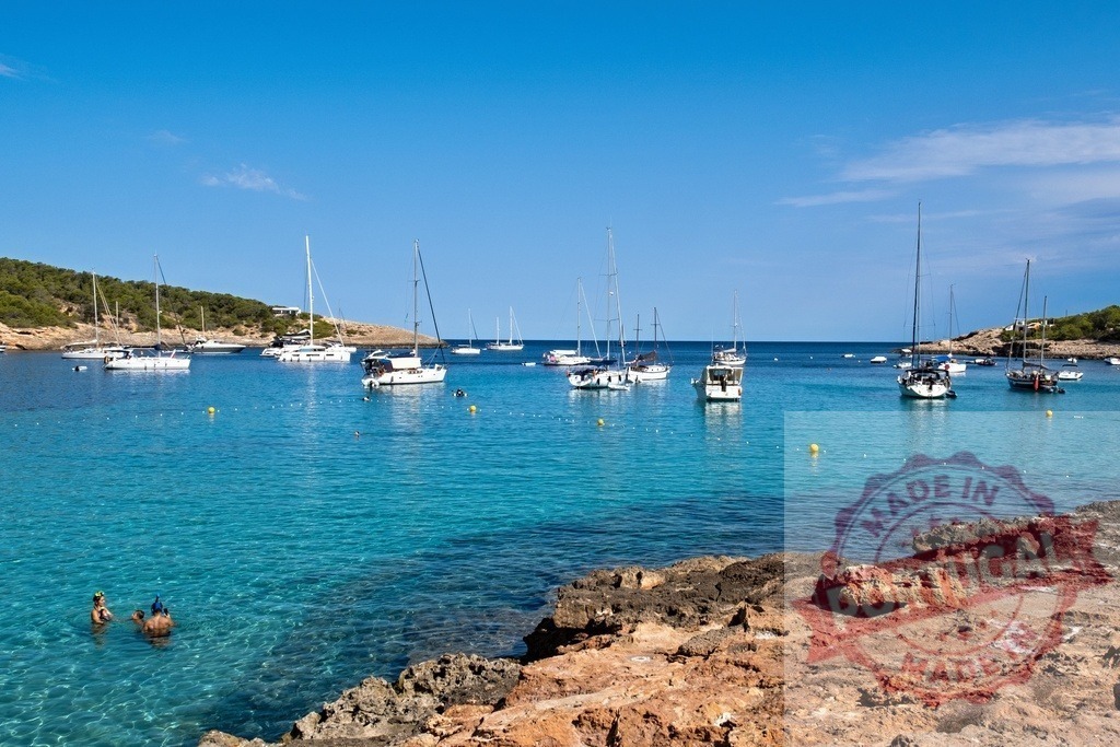 Boats anchoring in turquoise Cala Vedella bay, Ibiza | Sailboats and motorboats anchor in a clear turquoise bay with people swimming - Realized with Pictrs.com