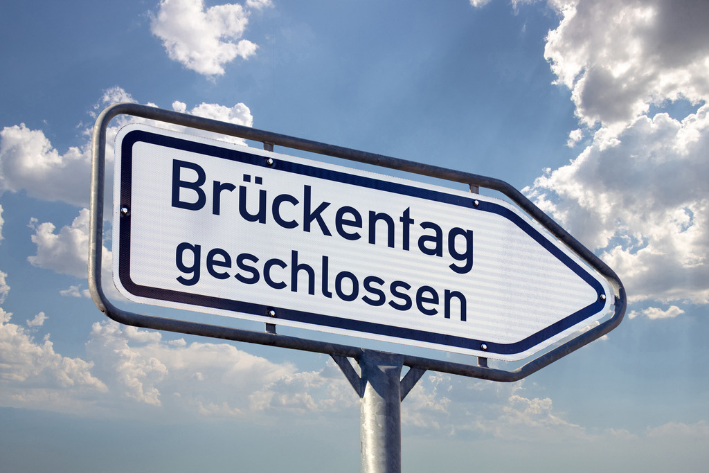 Schild BRÜCKENTAG GESCHLOSSEN | (Fotomontage) Richtungspfeil mit der Aufschrift BRÜCKENTAG GESCHLOSSEN vor blauem Himmel - Realisiert mit Pictrs.com