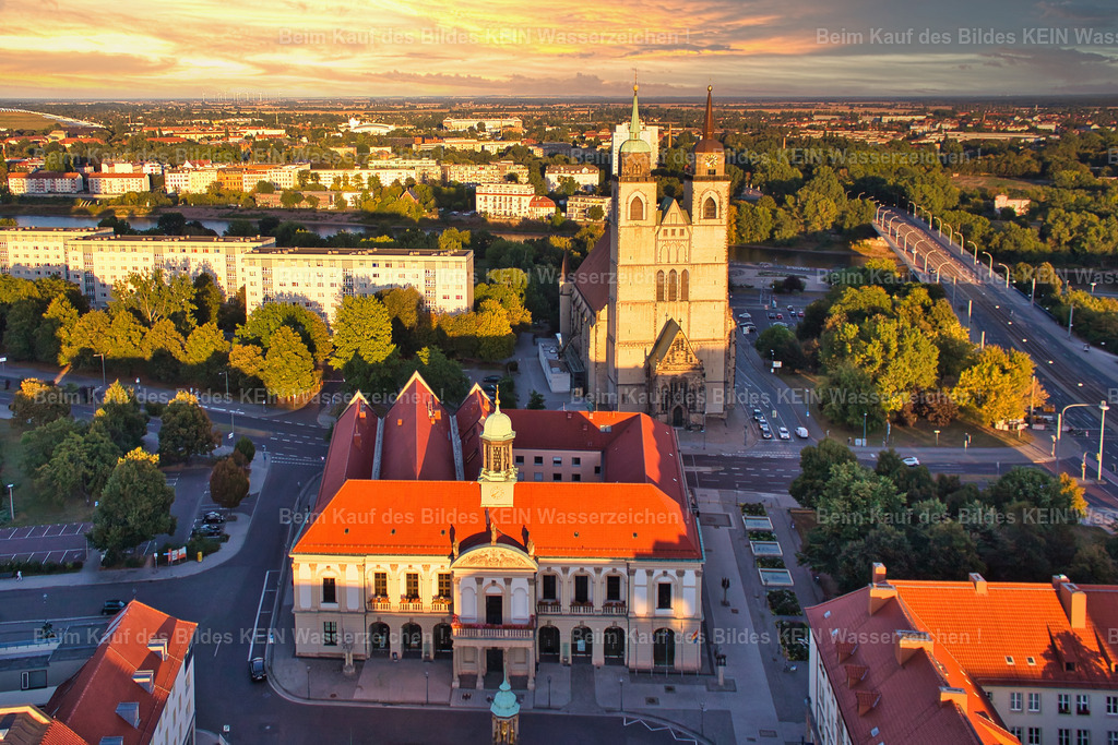 Rathaus-Magdeburg-Johanniskirche-Sonnenuntergang-Alter-Markt-0942 | Rathaus und Johanniskirche im warmen Abendlicht. Der tief stehende Sonnenstand lässt lange Schatten über die Magdeburger Innenstadt fallen und bringt die historischen Fassaden besonders plastisch zur Geltung.Beide Gebäude stehen für wichtige Kapitel der Magdeburger Stadtgeschichte. Das Rathaus am Alten Markt ist seit Jahrhunderten Mittelpunkt des politischen Lebens der Stadt. Die Johanniskirche gehört zu den ältesten Sakralbauten Magdeburgs und wurde nach den schweren Zerstörungen des Zweiten Weltkriegs wiederaufgebaut.Das besondere Licht macht aus der bekannten Stadtsilhouette eine ungewöhnliche Momentaufnahme. Die tief stehende Sonne zeichnet die Gebäude, Dächer und Straßen mit langen Schatten nach und verleiht der Innenstadt eine fast dreidimensionale Wirkung.Ein schönes Beispiel dafür, wie sich ein vertrauter Blick auf Magdeburg durch Jahreszeit, Sonnenstand und Licht immer wieder verändert. - Realisiert mit Pictrs.com