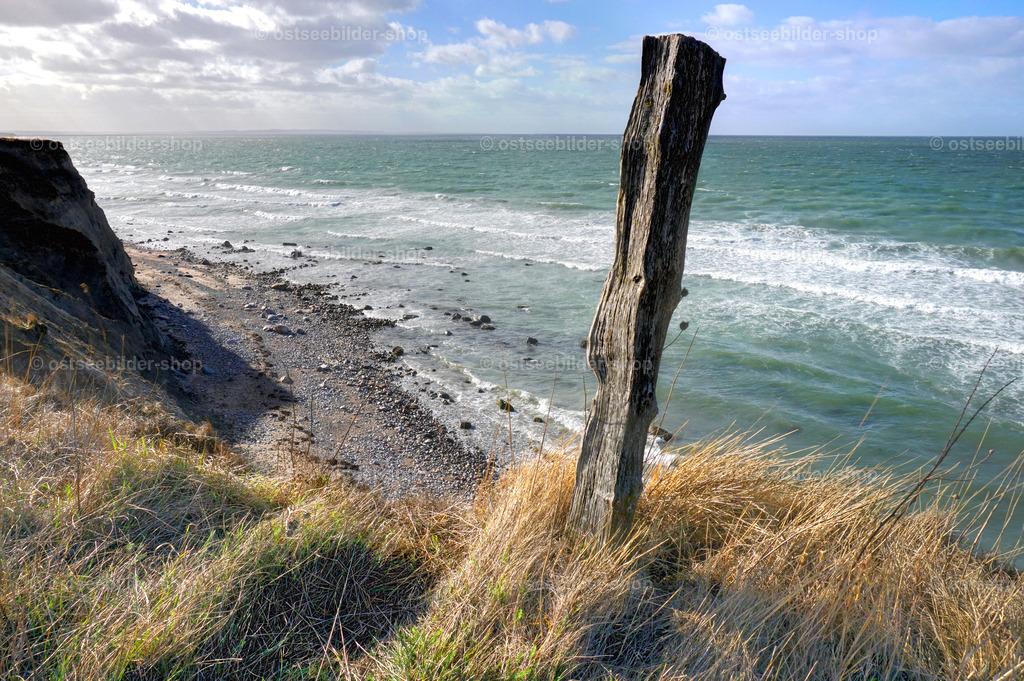 Zaunpfahl an Kliffkante | Ein Zaunpfahl steht nach mehreren Abbrüchen plötzlich dicht an der Steiluferkante und genießt einen tollen Blick auf die Wellen zu seinen Füßen.