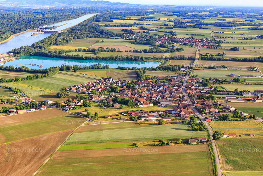Aerial view: Village view from the north in front of the gravel pit/gravel plant of Les Gravières Rhénanes SAS in Friesenheim in the state Bas-Rhin, France.Photo: IMG_147346.jpg taken on 05/29/2025 by Werner Riehm/FLY-FOTO.comResolution of the original: 5155 x 3437 pxCC Rhin - L'acu de la région