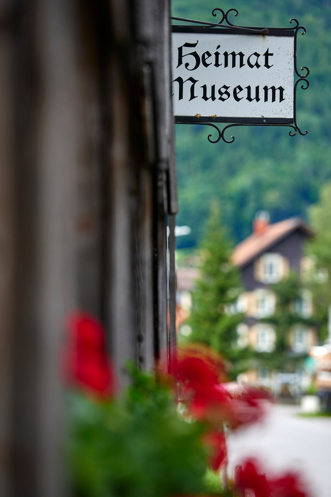 Heimatmuseum Bezau | Bezau, Austria - July 27, 2017: Heimatmuseum Bezau, Blick von der Seite auf das Heimatmuseums-Schild und den Blumen, im Hintergrund ein Bregenzerwaelderhaus. - Realisiert mit Pictrs.com