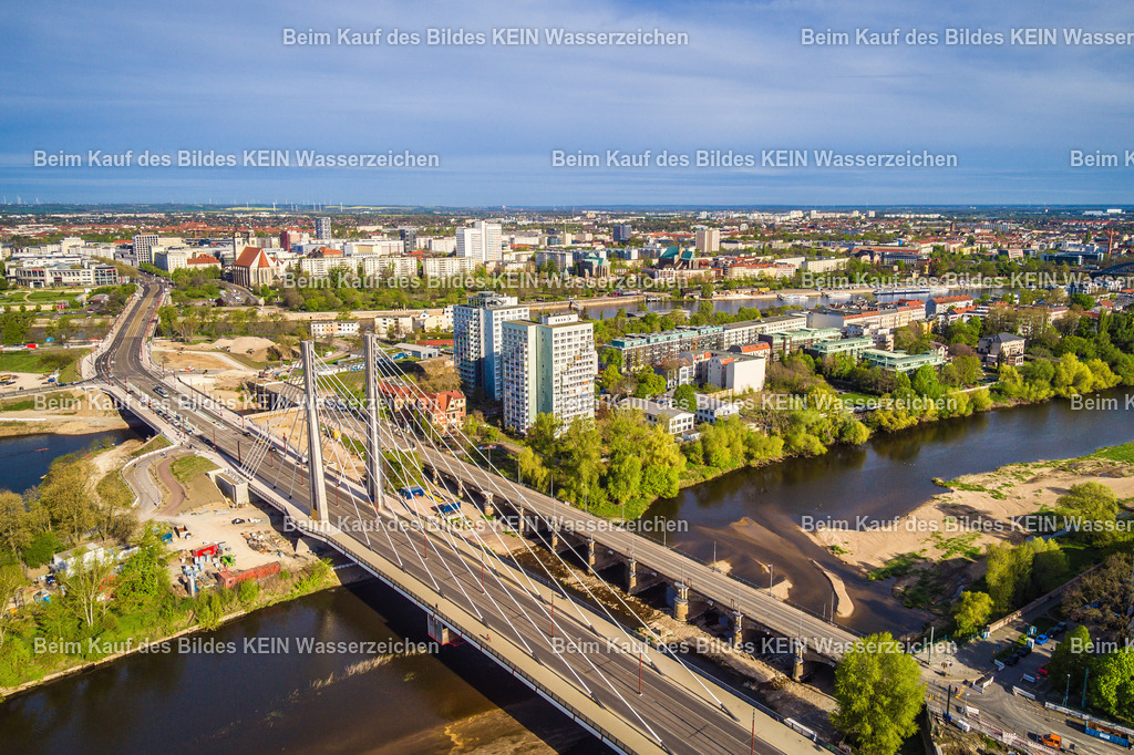 Luftbild Magdeburg Pylonbrücke Alte Elbe Werder-2 | Das Luftbild zeigt die Kaiser-Otto-Brücke in Magdeburg aus einer Drohnenperspektive. Die moderne Schrägseilbrücke überspannt die Alte Elbe mit ihrer markanten Pylonkonstruktion und zählt zu den bedeutendsten Ingenieurbauwerken der Landeshauptstadt. Aus der Vogelperspektive werden die symmetrisch angeordneten Schrägseile, der schlanke Brückenüberbau und die klare Linienführung besonders eindrucksvoll sichtbar.Die Kaiser-Otto-Brücke wurde zwischen **2020 und 2024** errichtet und ersetzt die frühere Anna-Ebert-Brücke. Das Bauwerk besitzt eine Gesamtlänge von 247,99 Metern und eine Breite von 27,10 Metern. Die Hauptöffnung überspannt die Alte Elbe mit einer Spannweite von 163,57 Metern. Charakteristisch sind die beiden 63 Meter hohen Pylone, von denen insgesamt 28 Schrägseile den Brückenüberbau tragen. Die Brücke verfügt über Fahrstreifen für den Individualverkehr, separate Gleise für Straßenbahnen sowie Geh- und Radwege und ist Bestandteil des Ersatzneubaus des Magdeburger Strombrückenzuges. Die Drohnenaufnahme verdeutlicht die moderne Ingenieurtechnik und die filigrane Konstruktion der Schrägseilbrücke. Die Kombination aus innovativer Brückenarchitektur, leistungsfähiger Verkehrsinfrastruktur und der markanten Silhouette macht die Kaiser-Otto-Brücke zu einem der bedeutendsten technischen Bauwerke Sachsen-Anhalts. - Realisiert mit Pictrs.com