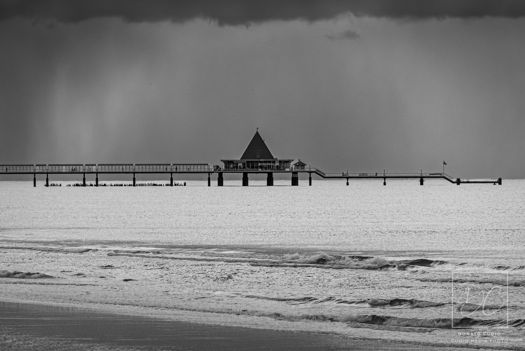 Stiller Horizont von Ahlbeck | Reduktion auf das Wesentliche: „Stiller Horizont von Ahlbeck“ zeigt die berühmte Seebrücke Usedom in einem Moment vollkommener Stille. Die kraftvolle Schwarzweiß-Komposition betont Struktur, Licht und Form – ganz ohne Ablenkung. Diese Fine-Art-Aufnahme vermittelt Ruhe, Klarheit und Zeitlosigkeit.Gedruckt auf hochwertigen Materialien wie Alu-Dibond, Acrylglas oder Leinwand – in Galeriequalität. Ideal für minimalistische Räume, moderne Büros oder Orte der Konzentration. - Realisiert mit Pictrs.com