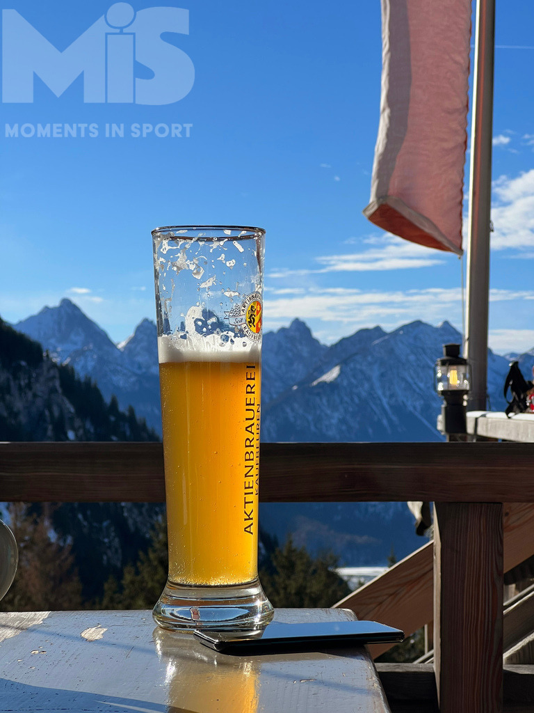 mis_110914bf01.JPG | 30.01.2022,  Schwangau bei Füssen im Allgäu, ein Wintertag auf der Rohrkopfhütte, eine Berghütte mit Bewirtung.  Auf dem Tisch vor dem Bergpanorama steht ein frisches Weissbier im Weissbierglas. - Realisiert mit Pictrs.com