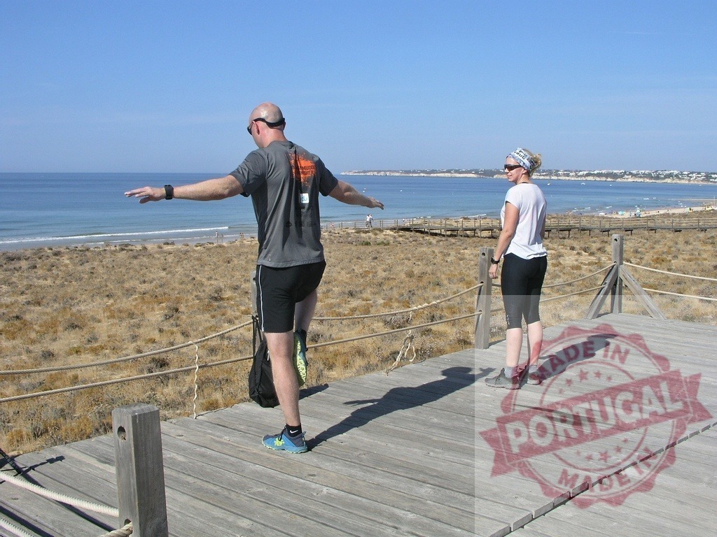Athletes practicing balance exercises on a wooden walkway by the sea | Two athletes practicing balance on one leg on a wooden walkway by the sea in a sunny day - Realisiert mit Pictrs.com