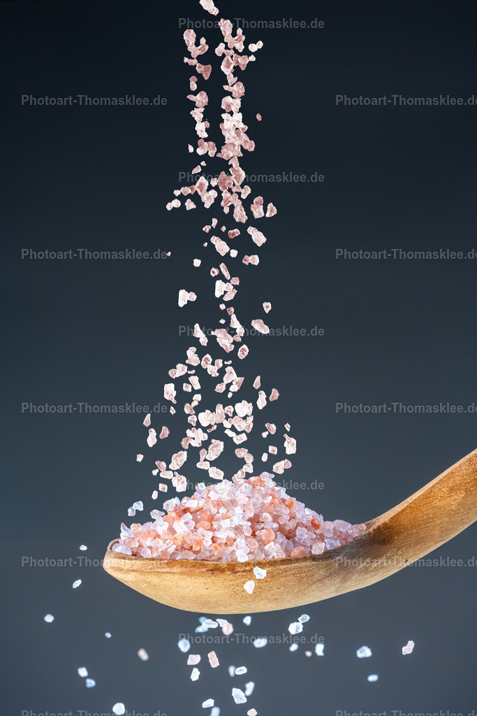 Rosa Kristalle – das Salz des Lebens | Rosa Kristalle – das Salz des Lebens. Kollektion: A spoon of tastefully seasonings.In dieser atmosphärischen Studioaufnahme fällt feines, zartrosa Himalaya-Kristallsalz in einer eingefrorenen Bewegung auf einen rustikalen, antiken Holzlöffel. Durch den Einsatz von Highspeed-Blitztechnik werden die filigranen Strukturen und die sanften Farbnuancen der Salzkristalle perfekt eingefangen. Der dunkle blaugraue Hintergrund bildet einen harmonischen Kontrast und hebt die edle Erscheinung des Salzes wirkungsvoll hervor. Die Kombination aus Naturmaterialien und kunstvoller Technik verleiht dem Motiv eine besondere Eleganz. Ideal geeignet für Räume, die Wert auf Stil, Natürlichkeit und feine Details legen – sei es privat oder im gehobenen gewerblichen Bereich.Wo könnte man dieses Bild am besten aufhängen?Privater Bereich:In einer stilvollen Küche, um eine luxuriöse und naturverbundene Atmosphäre zu schaffen.Im Essbereich, besonders in einer modernen oder rustikalen Einrichtung, wo feine Details geschätzt werden.Gewerblicher Bereich:In einem Feinkostgeschäft oder Delikatessenladen als Blickfang bei der Präsentation hochwertiger Produkte.In einem Spa oder Wellnessbereich, wo Naturmaterialien und entspannende Farben eine zentrale Rolle spielen.Alu-Dibond: Bietet eine matte, hochwertige Oberfläche, die die zarten Rosa- und Naturtöne des Salzes klar und edel zur Geltung bringt.Acrylglas: Verstärkt die Lichtbrechung und Tiefenwirkung der fallenden Kristalle und sorgt für ein luxuriöses, strahlendes Finish.Poster: Ideal für flexible Raumgestaltungen, um mit wenig Aufwand Eleganz und Natürlichkeit in Küche oder Wellnessräume zu bringen.Leinwand: Verleiht dem Motiv eine warme, leicht strukturierte Oberfläche, die die rustikale Note des Holzlöffels und die natürliche Schönheit des Salzes unterstreicht. - Realisiert mit Pictrs.com